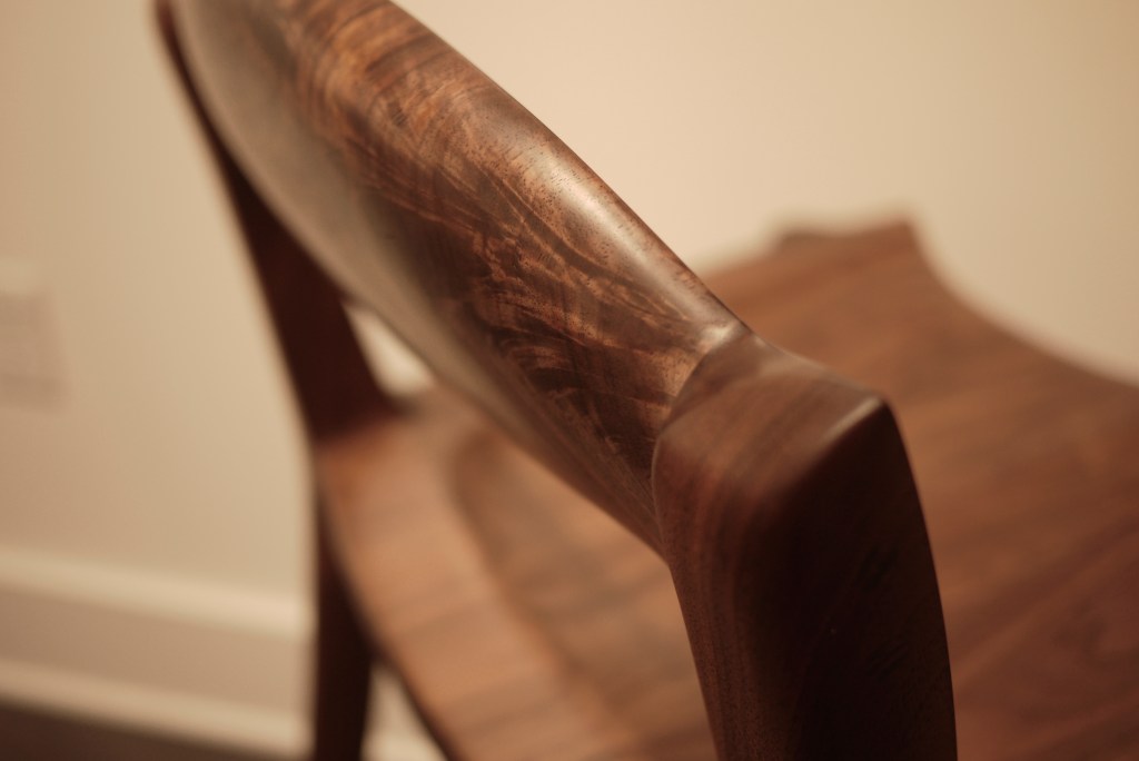 closeup on walnut figure of hand shaped chair back