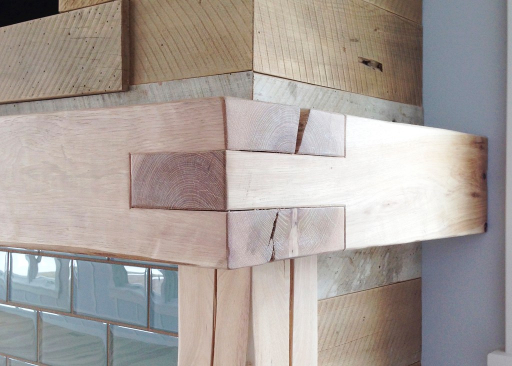 hand hewn hickory mantle finished with soap next to barn wood and turquoise tile