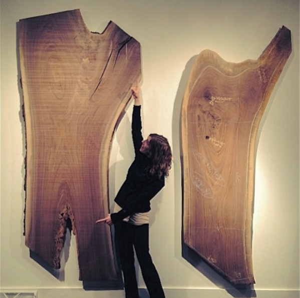 two walnut slabs hanging on wall with woman in black and cream background
